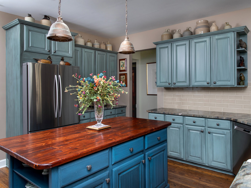 Foto på ett avskilt, mellanstort flerfärgad kök, med en rustik diskho, luckor med upphöjd panel, blå skåp, granitbänkskiva, beige stänkskydd, stänkskydd i tunnelbanekakel, rostfria vitvaror, mellanmörkt trägolv, en köksö och brunt golv