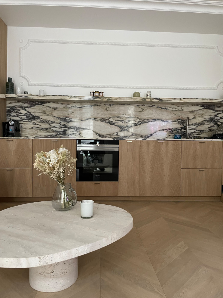 Photo of a medium sized contemporary single-wall open plan kitchen in Paris with a submerged sink, beaded cabinets, light wood cabinets, marble worktops, beige splashback, marble splashback, integrated appliances, plywood flooring, no island, beige floors and beige worktops.