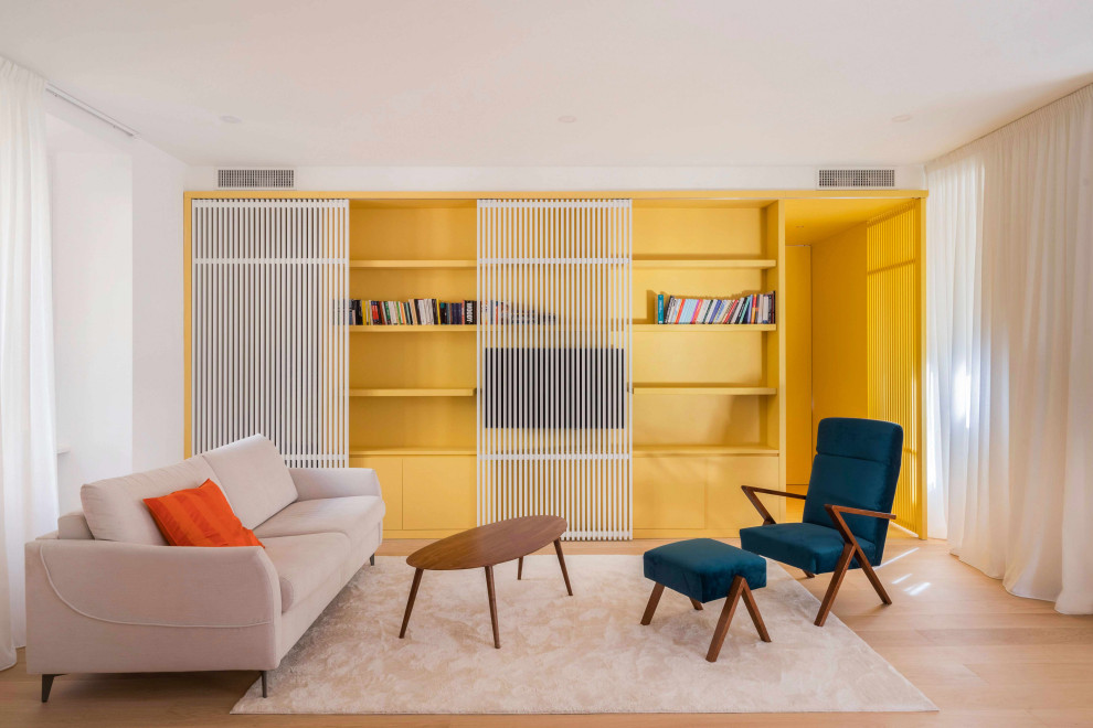 Kleine, Offene Moderne Bibliothek mit gelber Wandfarbe, hellem Holzboden, verstecktem TV, beigem Boden und vertäfelten Wänden in Rom