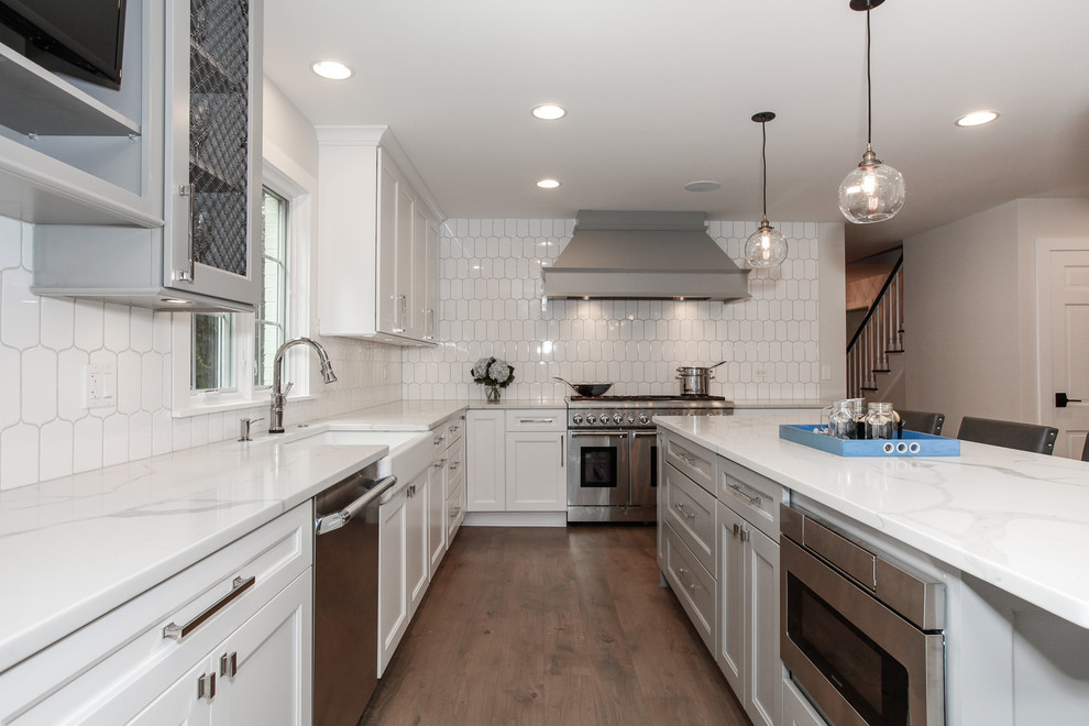 Design ideas for a large transitional l-shaped open plan kitchen in Chicago with a farmhouse sink, recessed-panel cabinets, white cabinets, marble benchtops, white splashback, porcelain splashback, stainless steel appliances, medium hardwood floors and with island.