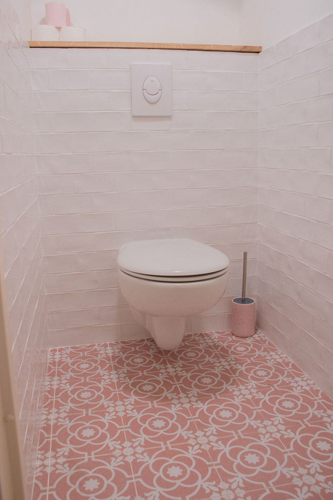 На фото: главная ванная комната среднего размера в стиле модернизм с инсталляцией, белой плиткой, керамической плиткой, белыми стенами, полом из цементной плитки, консольной раковиной, розовым полом, душем с раздвижными дверями и тумбой под одну раковину с
