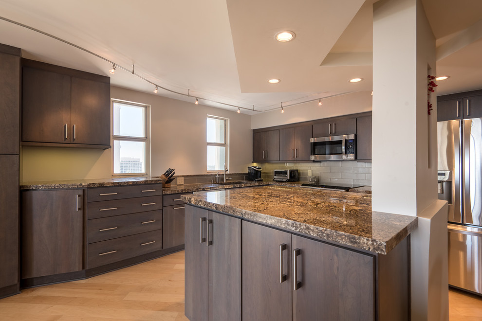Photo of a mid-sized contemporary l-shaped eat-in kitchen in San Diego with an undermount sink, flat-panel cabinets, dark wood cabinets, granite benchtops, grey splashback, glass tile splashback, stainless steel appliances, light hardwood floors and with island.