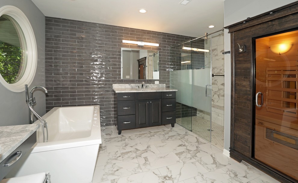 Large transitional gray tile and subway tile porcelain tile and white floor freestanding bathtub photo with raised-panel cabinets, gray cabinets, gray walls, an undermount sink and granite countertops