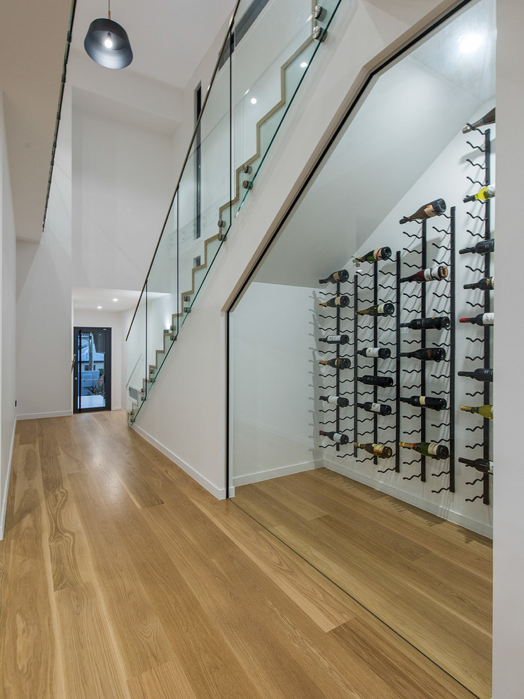 Inspiration for a contemporary wine cellar in Brisbane with light hardwood floors, storage racks and yellow floor.