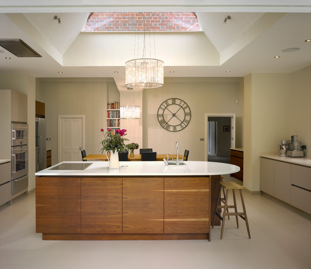 Large contemporary open plan kitchen in London with an undermount sink, flat-panel cabinets, medium wood cabinets, solid surface benchtops, stainless steel appliances and with island.