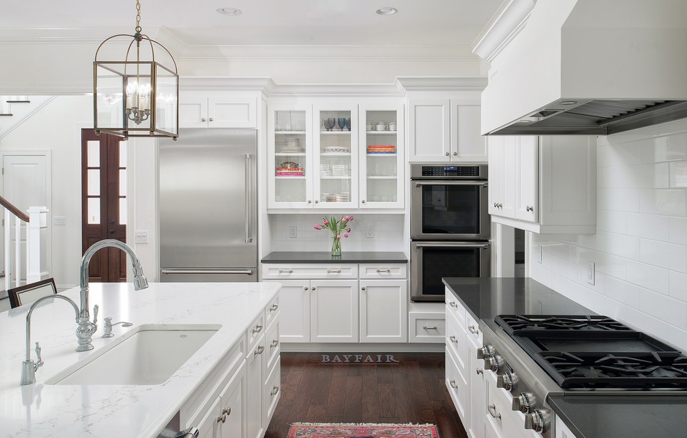 This is an example of a large transitional l-shaped open plan kitchen in Tampa with an undermount sink, recessed-panel cabinets, white cabinets, marble benchtops, white splashback, subway tile splashback, stainless steel appliances, dark hardwood floors, with island and brown floor.