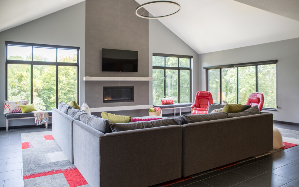 Photo of a mid-sized modern enclosed living room in Cedar Rapids with grey walls, a standard fireplace, slate floors, a concrete fireplace surround, a wall-mounted tv, grey floor and vaulted.