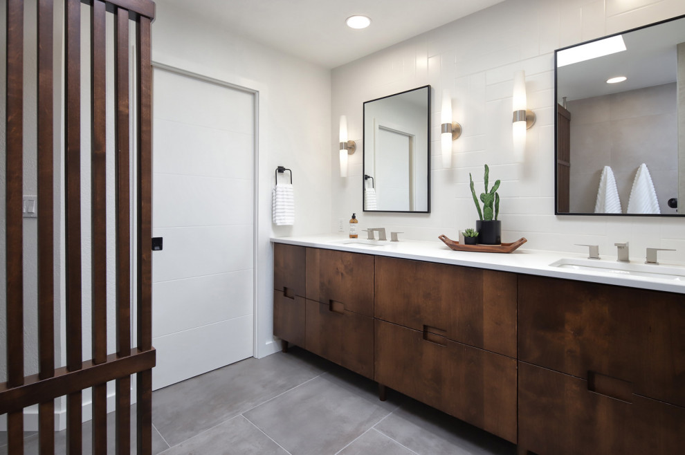 This is an example of a mid-sized midcentury master bathroom in Phoenix with flat-panel cabinets, medium wood cabinets, a curbless shower, a one-piece toilet, gray tile, porcelain tile, white walls, porcelain floors, an undermount sink, engineered quartz benchtops, grey floor, an open shower, white benchtops, a niche, a double vanity, a built-in vanity and wood walls.