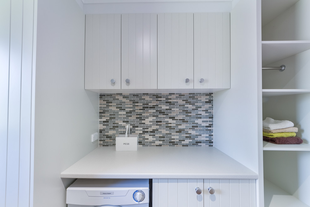 Photo of a small contemporary galley dedicated laundry room in Sydney with recessed-panel cabinets, white cabinets, laminate benchtops, medium hardwood floors and white walls.