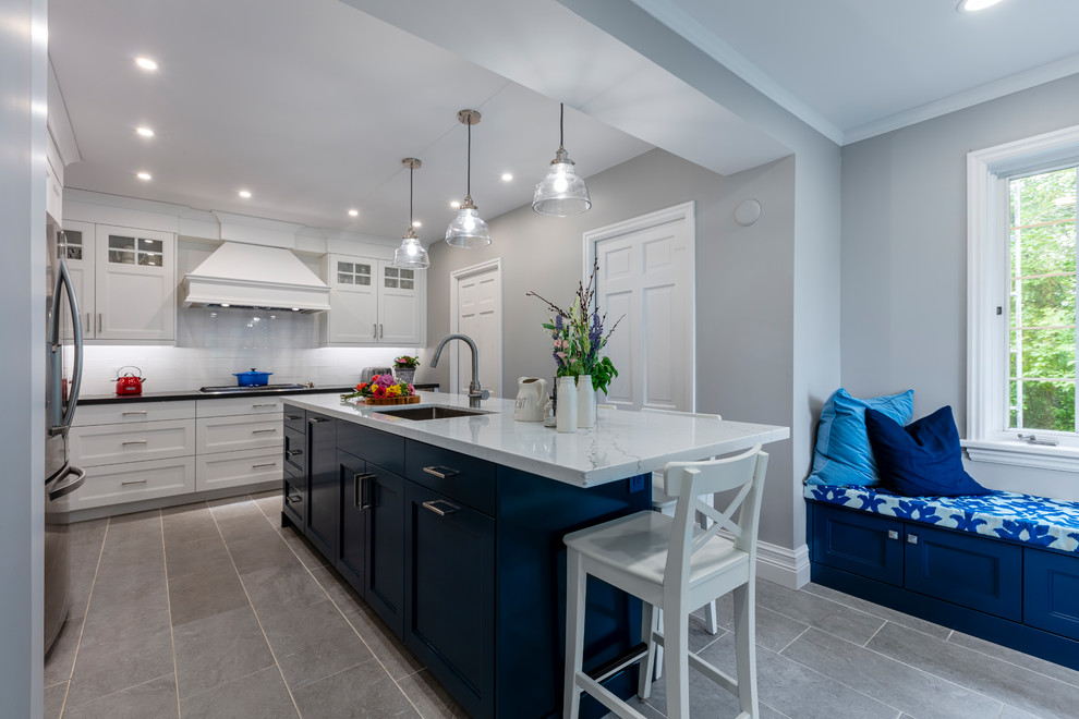 Inspiration for a mid-sized transitional l-shaped eat-in kitchen in Toronto with an undermount sink, shaker cabinets, white cabinets, quartz benchtops, white splashback, porcelain splashback, stainless steel appliances, porcelain floors, with island, grey floor and multi-coloured benchtop.