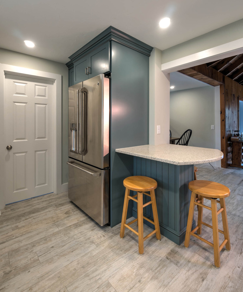 This is an example of a small modern l-shaped kitchen pantry in Boston with a farmhouse sink, shaker cabinets, blue cabinets, recycled glass benchtops, white splashback, ceramic splashback, stainless steel appliances, ceramic floors, with island and beige floor.