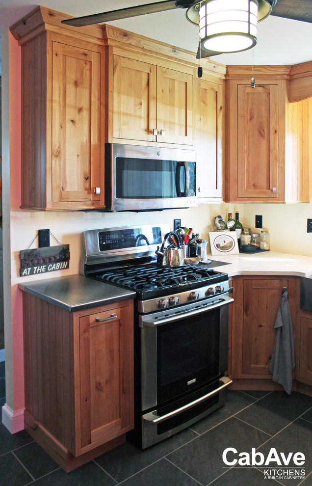 Inspiration for a small rustic u-shaped slate floor and gray floor enclosed kitchen remodel with a farmhouse sink, recessed-panel cabinets, medium tone wood cabinets, quartz countertops, stainless steel appliances and no island