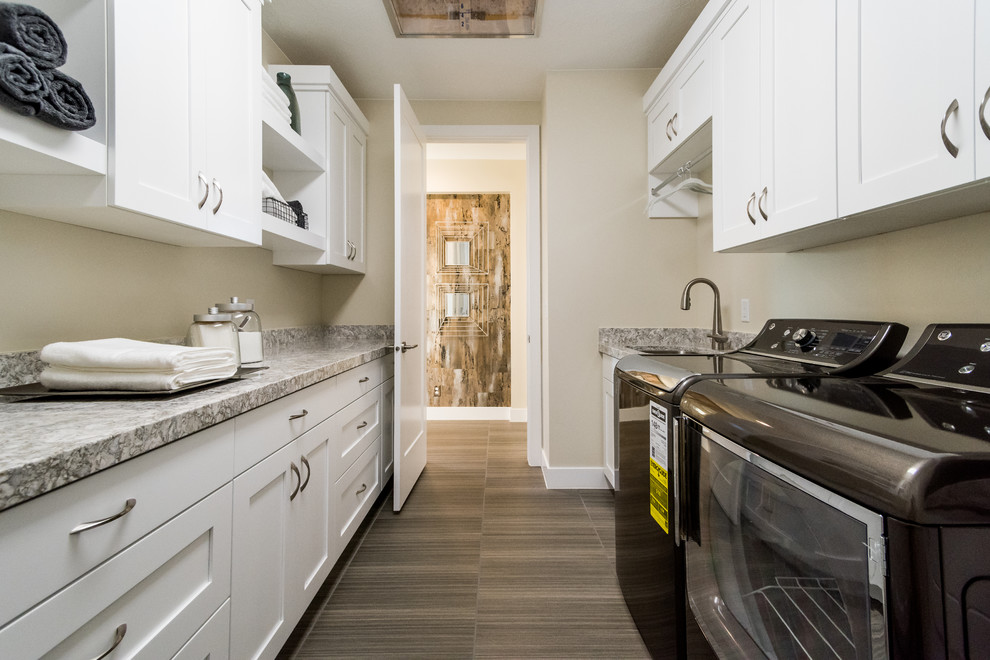 Inspiration for a mid-sized contemporary galley dedicated laundry room in Salt Lake City with an undermount sink, shaker cabinets, white cabinets, granite benchtops, beige walls, vinyl floors and a side-by-side washer and dryer.
