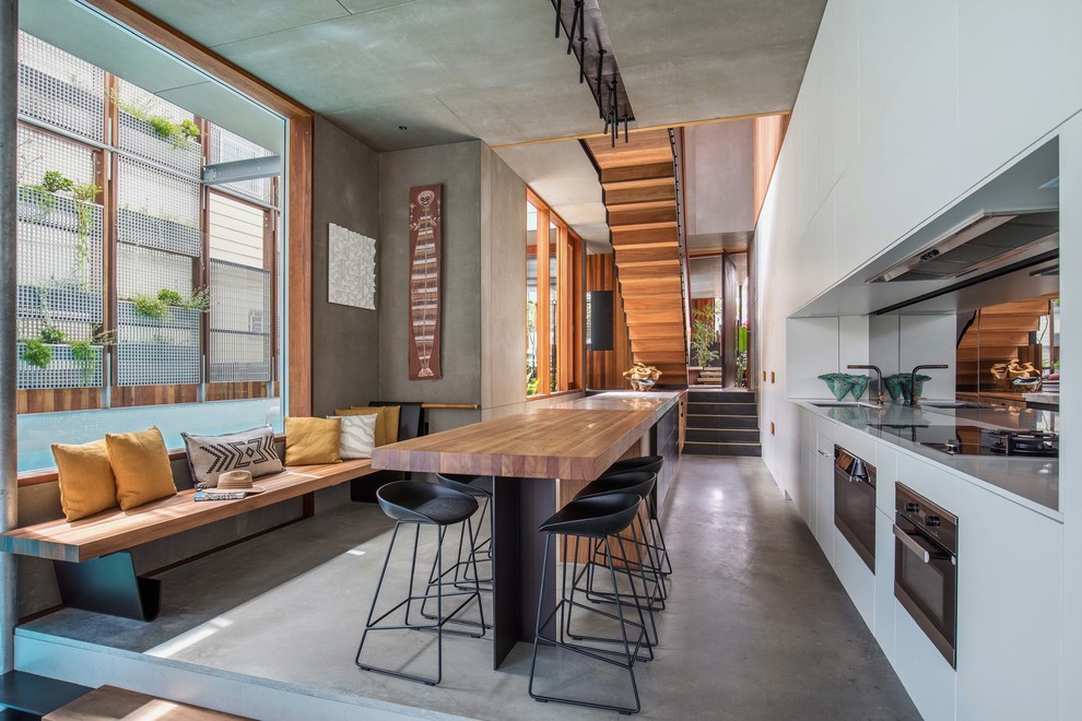 Contemporary kitchen in Sydney with an undermount sink, flat-panel cabinets, white cabinets, concrete floors, with island and grey floor.