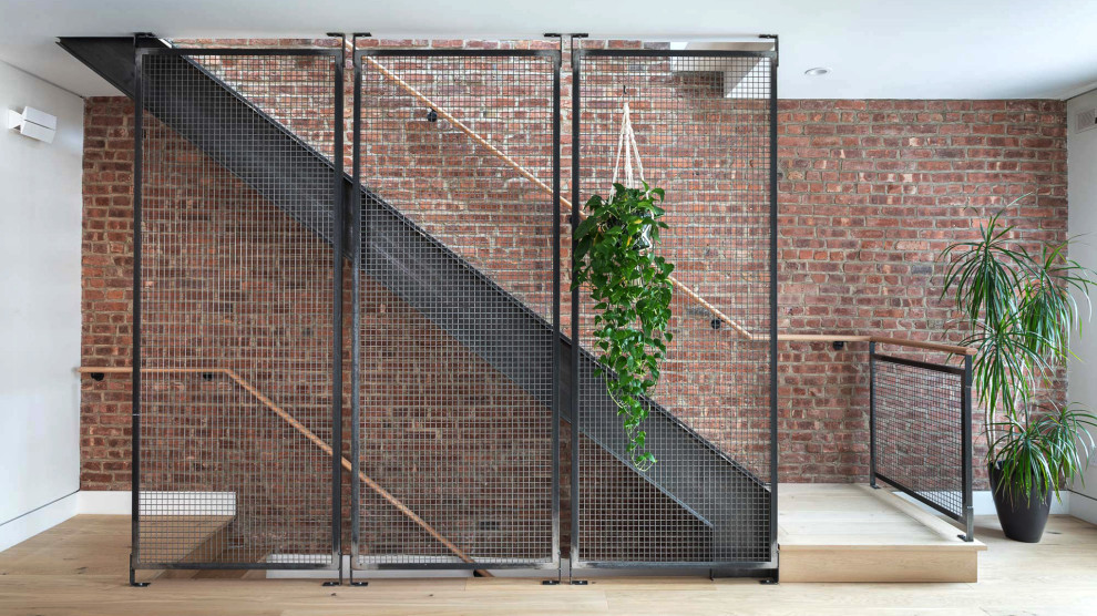 Inspiration pour un escalier sans contremarche droit minimaliste de taille moyenne avec des marches en bois, un garde-corps en métal et un mur en parement de brique.