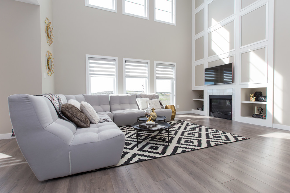 This is an example of a large transitional open concept living room in Other with beige walls, laminate floors, a standard fireplace, a tile fireplace surround and a wall-mounted tv.