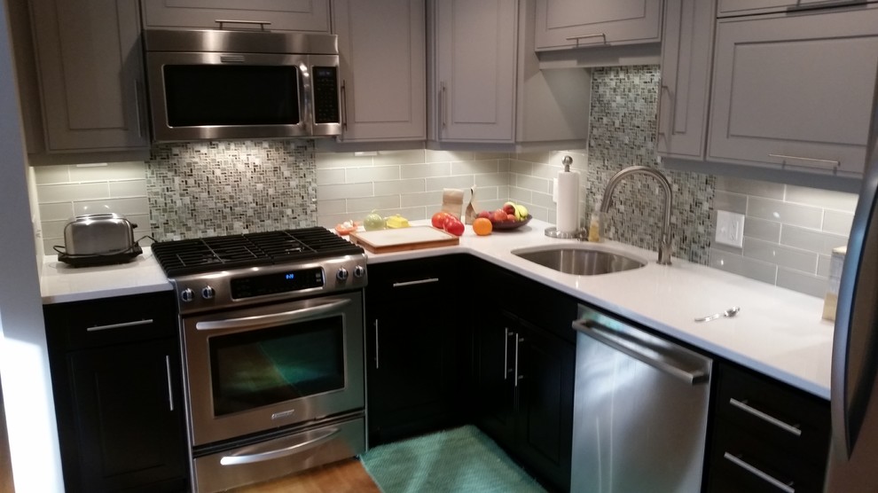Small transitional l-shaped light wood floor eat-in kitchen photo in Detroit with an undermount sink, raised-panel cabinets, gray cabinets, quartz countertops, gray backsplash, glass tile backsplash, stainless steel appliances and no island