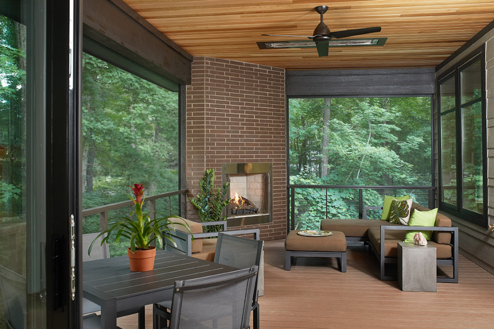 This is an example of a midcentury backyard screened-in verandah in Grand Rapids with decking and a roof extension.
