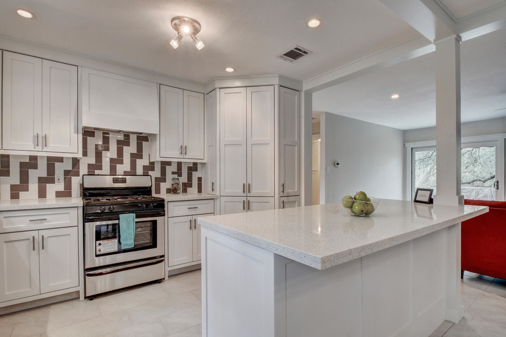 Example of a mid-sized transitional l-shaped porcelain tile and white floor kitchen design in Austin with a farmhouse sink, shaker cabinets, white cabinets, quartz countertops, multicolored backsplash, ceramic backsplash, stainless steel appliances, a peninsula and white countertops