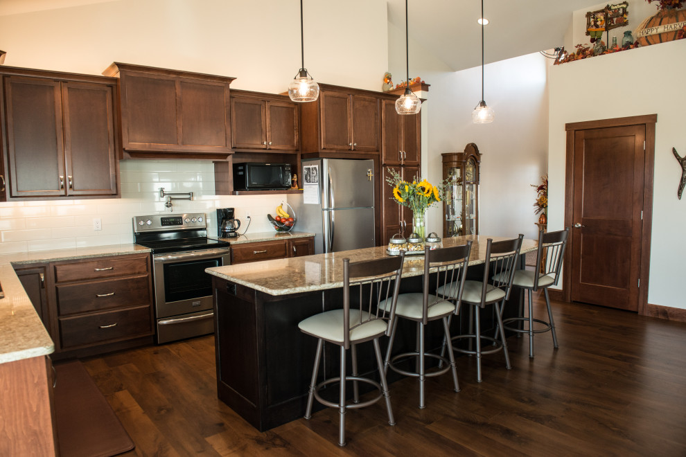 Large transitional l-shaped medium tone wood floor open concept kitchen photo with an undermount sink, flat-panel cabinets, medium tone wood cabinets, quartz countertops, white backsplash, ceramic backsplash, stainless steel appliances, an island and multicolored countertops