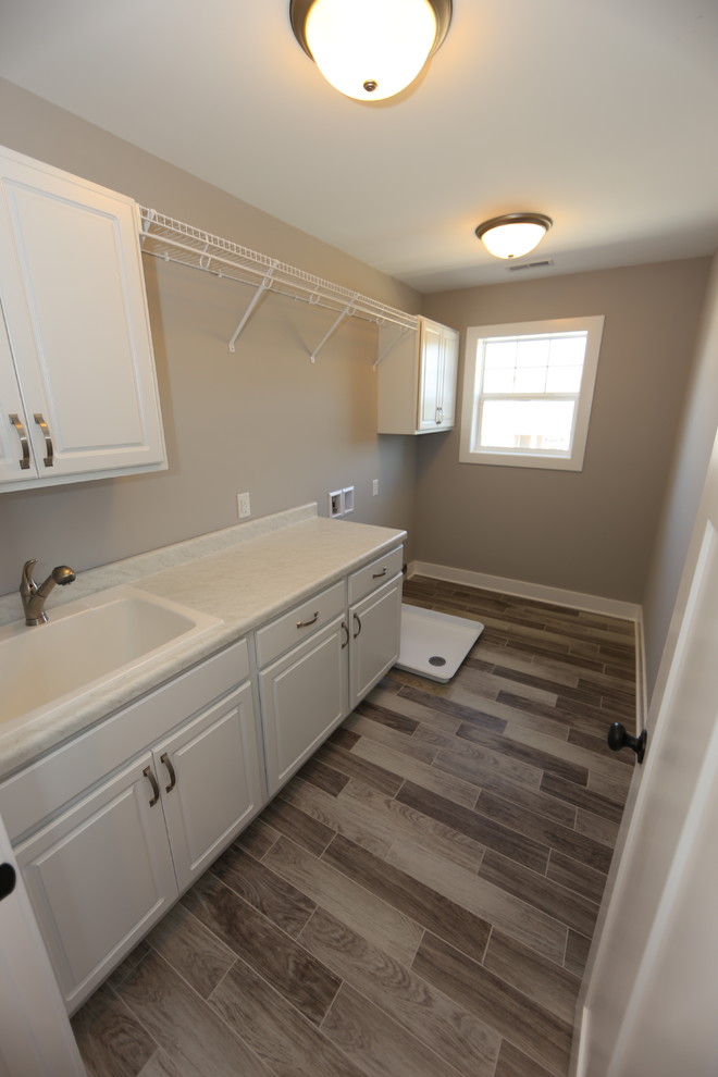 Design ideas for a large transitional single-wall dedicated laundry room in Chicago with a drop-in sink, raised-panel cabinets, white cabinets, quartzite benchtops, grey walls, vinyl floors and a side-by-side washer and dryer.