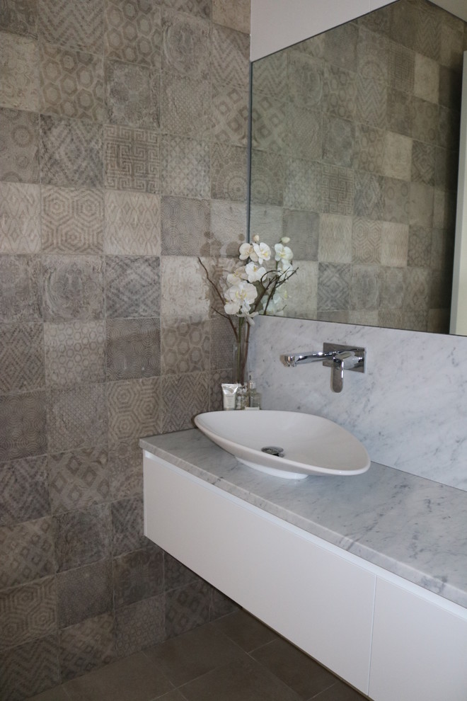 Photo of a contemporary powder room in Sydney with furniture-like cabinets and marble benchtops.