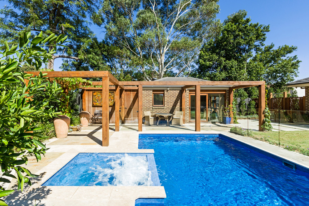 Mid-sized mediterranean backyard rectangular lap pool in Melbourne with a pool house and natural stone pavers.