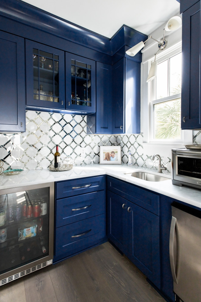 Foto di un angolo bar stile marinaro di medie dimensioni con lavello sottopiano, ante in stile shaker, ante blu, paraspruzzi bianco, pavimento in legno massello medio e top bianco