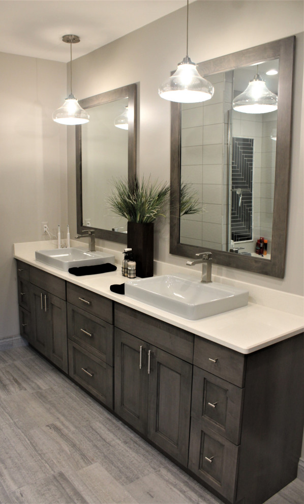 This is an example of a large transitional master bathroom in Detroit with recessed-panel cabinets, medium wood cabinets, an open shower, a two-piece toilet, black and white tile, ceramic tile, grey walls, porcelain floors, a vessel sink, engineered quartz benchtops, grey floor, a hinged shower door, white benchtops, a shower seat, a double vanity and a freestanding vanity.