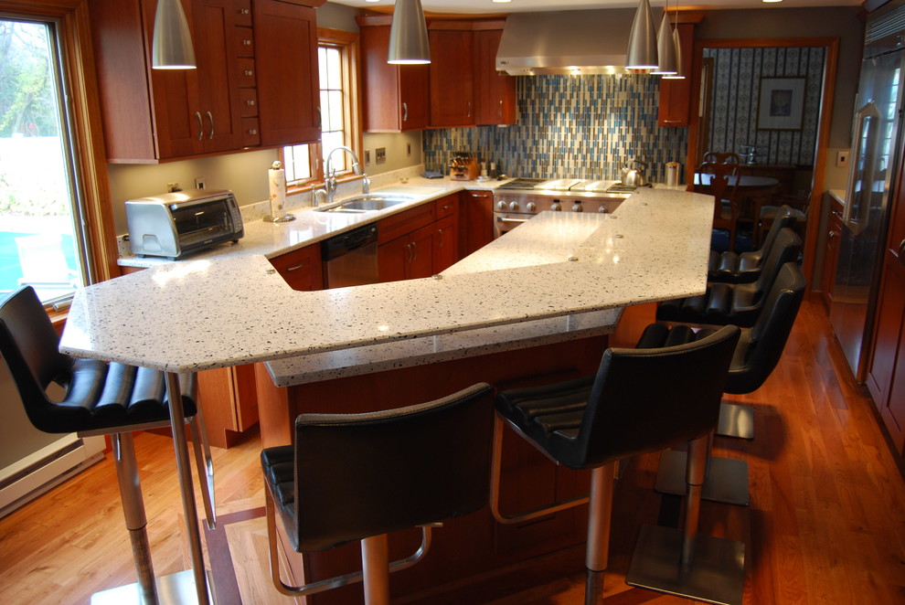 Open concept kitchen - mid-sized transitional l-shaped medium tone wood floor and brown floor open concept kitchen idea in Boston with an undermount sink, shaker cabinets, medium tone wood cabinets, recycled glass countertops, glass tile backsplash, stainless steel appliances, an island and beige backsplash
