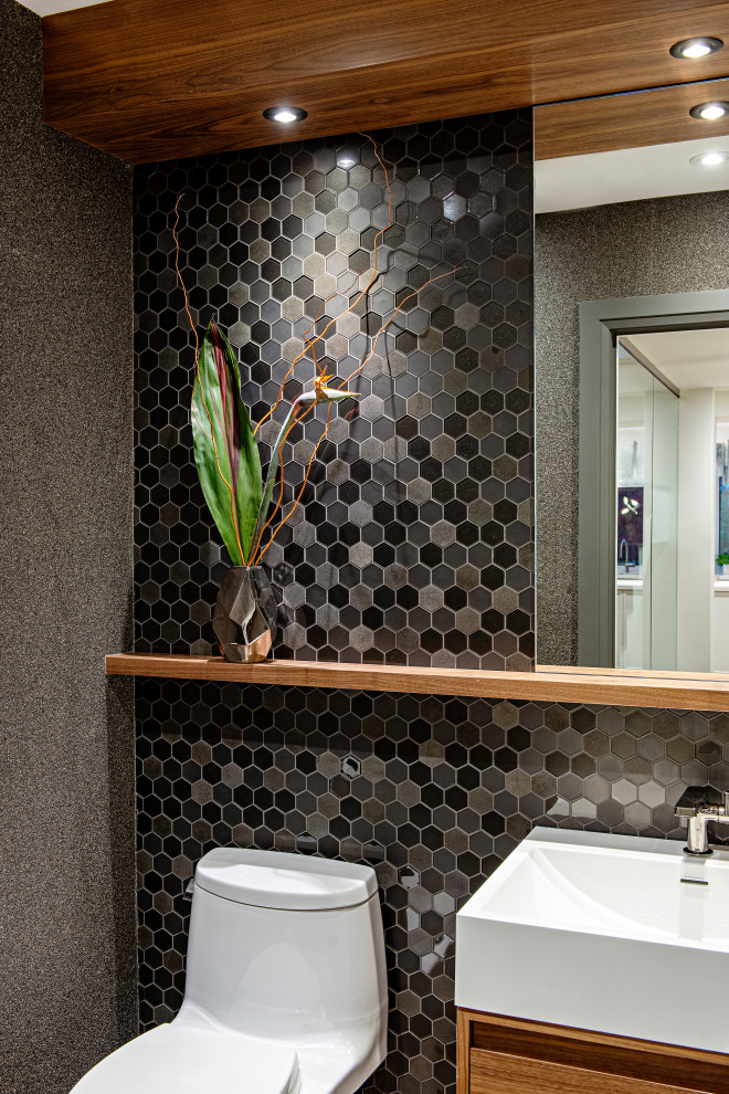 Photo of a small contemporary powder room in Toronto with medium wood cabinets, a one-piece toilet, black tile, mosaic tile, black walls, white benchtops, a floating vanity and wallpaper.