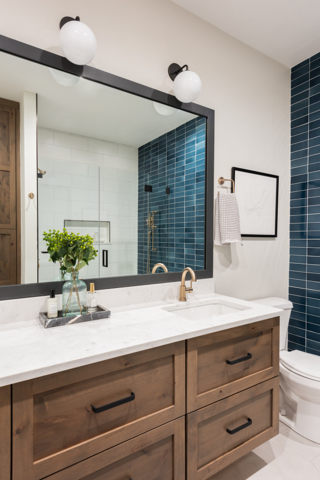 This is an example of a small transitional master bathroom in Chicago with recessed-panel cabinets, medium wood cabinets, an alcove shower, a one-piece toilet, blue tile, ceramic tile, white walls, mosaic tile floors, a drop-in sink, engineered quartz benchtops, beige floor, a hinged shower door, white benchtops, a double vanity and a floating vanity.