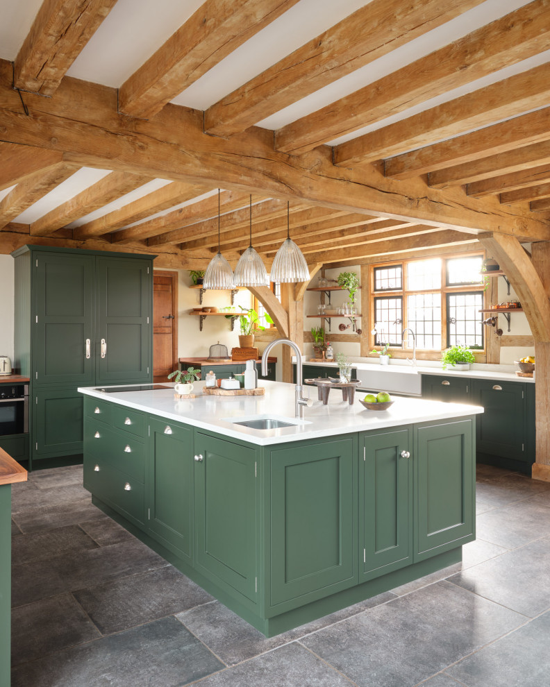 Design ideas for a country u-shaped kitchen in Gloucestershire with a farmhouse sink, shaker cabinets, green cabinets, panelled appliances, with island, grey floor, white benchtop and exposed beam.
