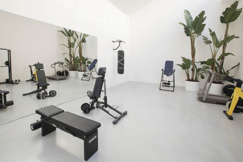 Photo of a mid-sized industrial home weight room in Milan with white walls, concrete floors and grey floor.