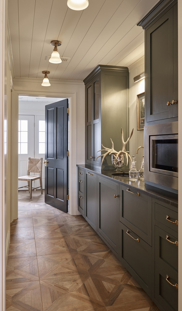 Mid-sized traditional galley wet bar in Other with flat-panel cabinets, green cabinets, soapstone benchtops, white splashback, timber splashback, porcelain floors and black benchtop.