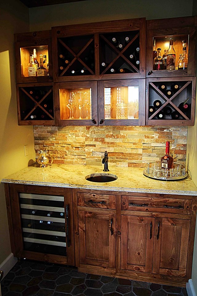 Small country single-wall wet bar in Other with an undermount sink, brown cabinets, granite benchtops, brown splashback, stone tile splashback and shaker cabinets.