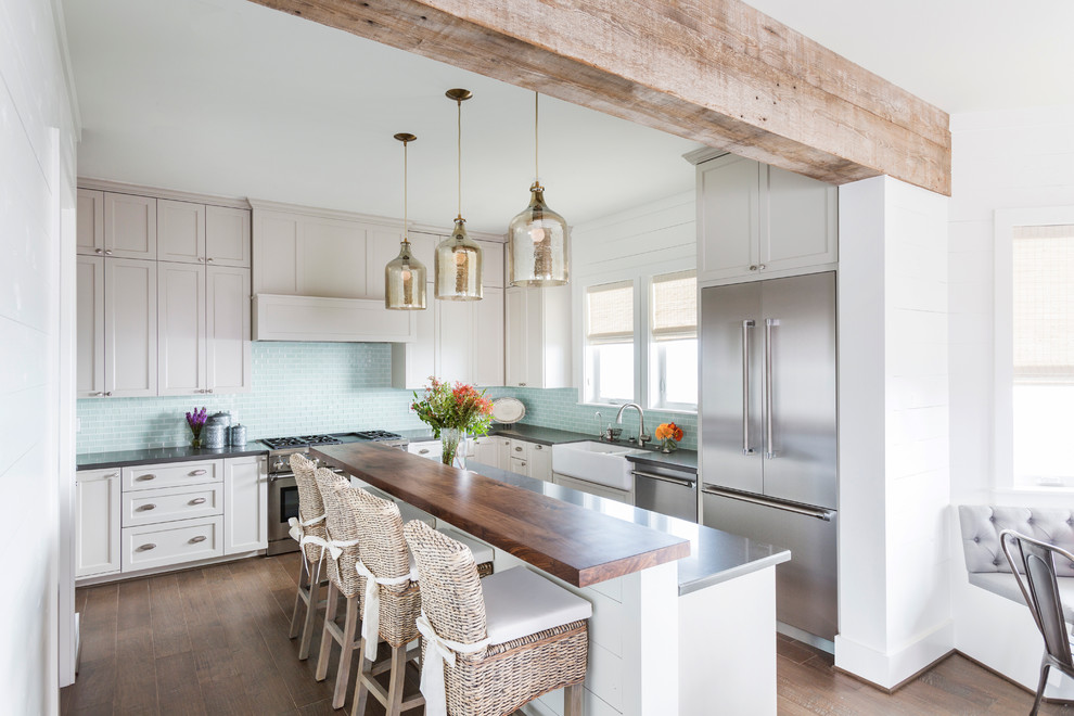 Photo of a beach style u-shaped eat-in kitchen in Houston with a double-bowl sink, raised-panel cabinets, white cabinets, zinc benchtops, blue splashback, ceramic splashback, stainless steel appliances, with island and dark hardwood floors.
