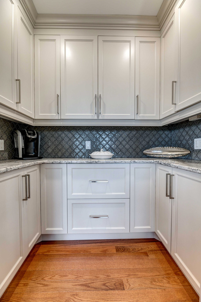 Eat-in kitchen - large transitional l-shaped medium tone wood floor eat-in kitchen idea with an undermount sink, shaker cabinets, granite countertops, porcelain backsplash, stainless steel appliances and an island
