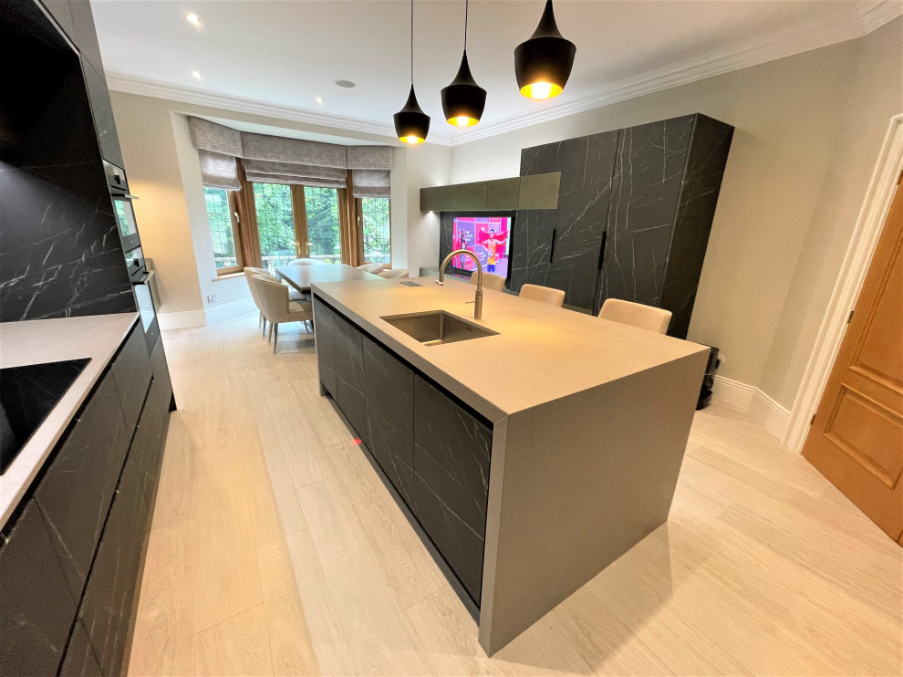 Inspiration for a large contemporary l-shaped eat-in kitchen in Other with a single-bowl sink, flat-panel cabinets, black cabinets, solid surface benchtops, black appliances, porcelain floors and with island.