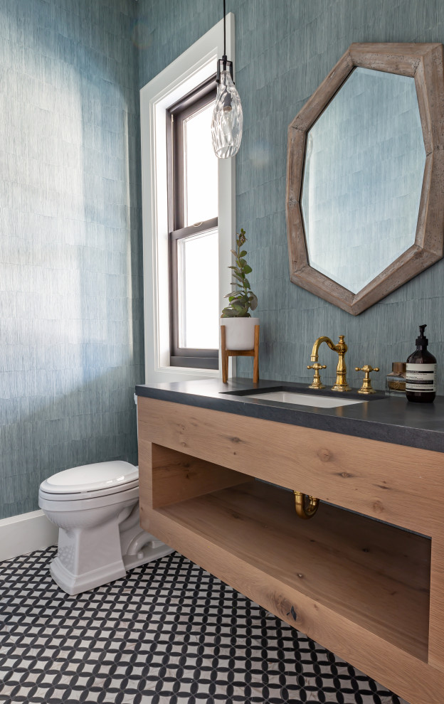 Photo of a mid-sized country powder room in San Francisco with light wood cabinets, blue walls, marble floors, an undermount sink, granite benchtops, multi-coloured floor, black benchtops, a floating vanity, wallpaper and open cabinets.