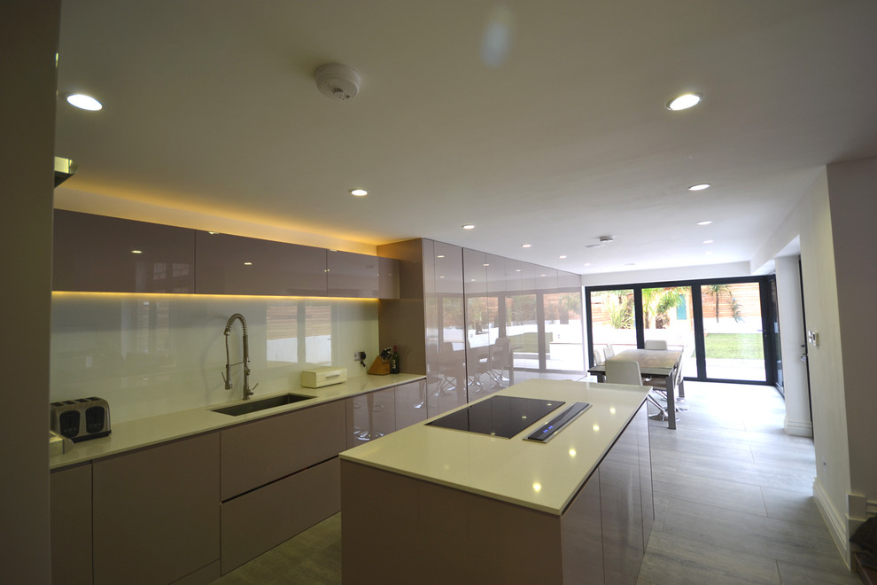 Mid-sized contemporary l-shaped eat-in kitchen in London with an integrated sink, flat-panel cabinets, medium wood cabinets, quartzite benchtops, white splashback, black appliances, medium hardwood floors and with island.