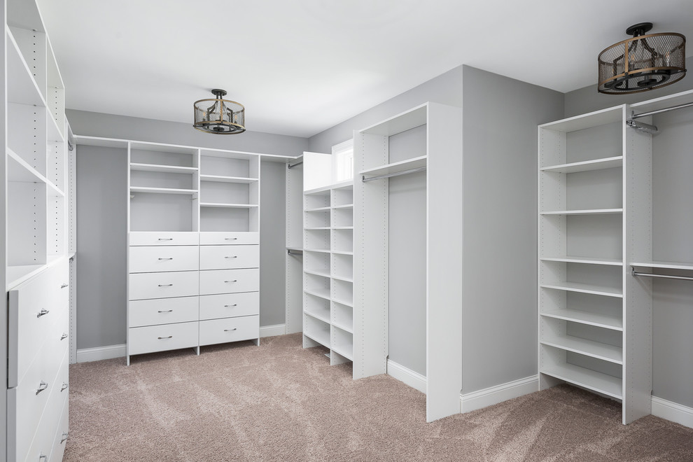 Inspiration for an expansive country gender-neutral walk-in wardrobe in Chicago with flat-panel cabinets, white cabinets, carpet and beige floor.