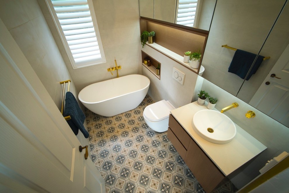 Inspiration for a mid-sized contemporary bathroom in Sydney with medium wood cabinets, a freestanding tub, beige tile, porcelain tile, beige walls, cement tiles, a drop-in sink, multi-coloured floor and white benchtops.