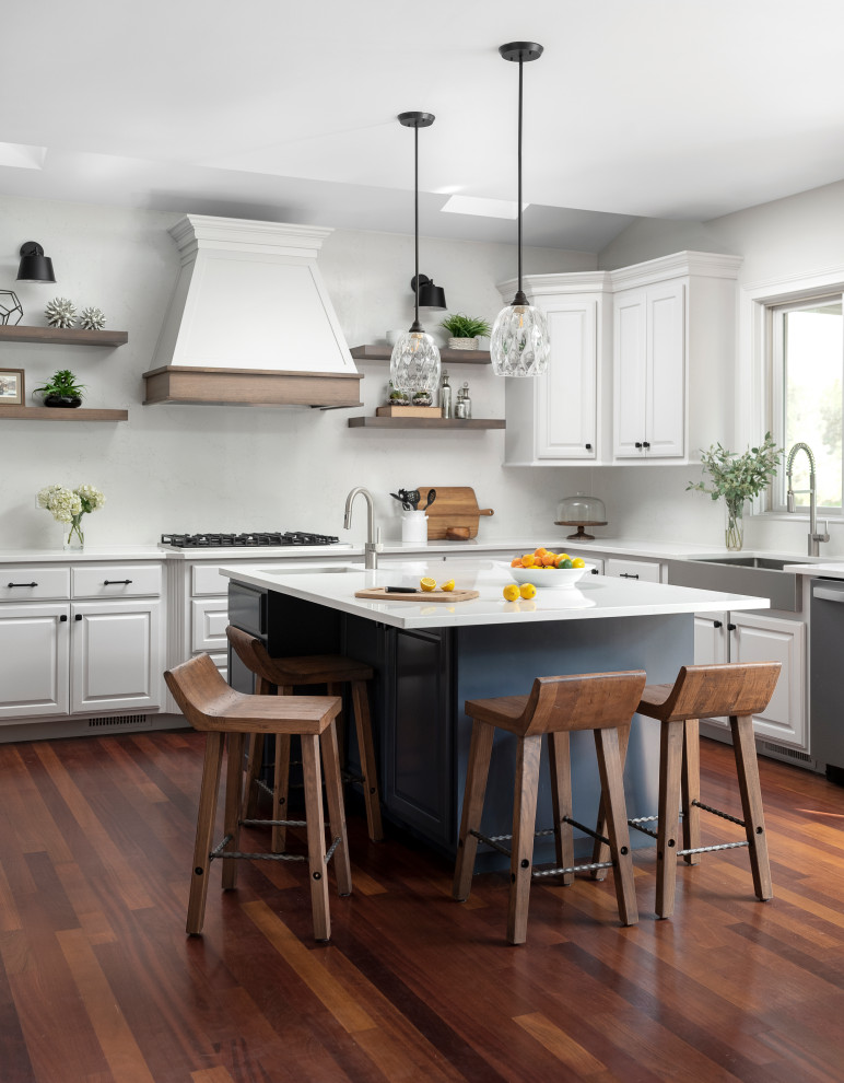 This is an example of a large transitional u-shaped eat-in kitchen in Chicago with a farmhouse sink, raised-panel cabinets, grey cabinets, quartz benchtops, white splashback, engineered quartz splashback, stainless steel appliances, medium hardwood floors, with island, white benchtop and vaulted.