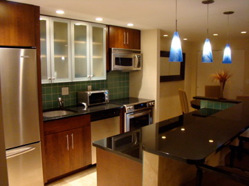 Photo of a contemporary single-wall eat-in kitchen in Philadelphia with an undermount sink, flat-panel cabinets, medium wood cabinets, granite benchtops, green splashback, glass tile splashback and stainless steel appliances.