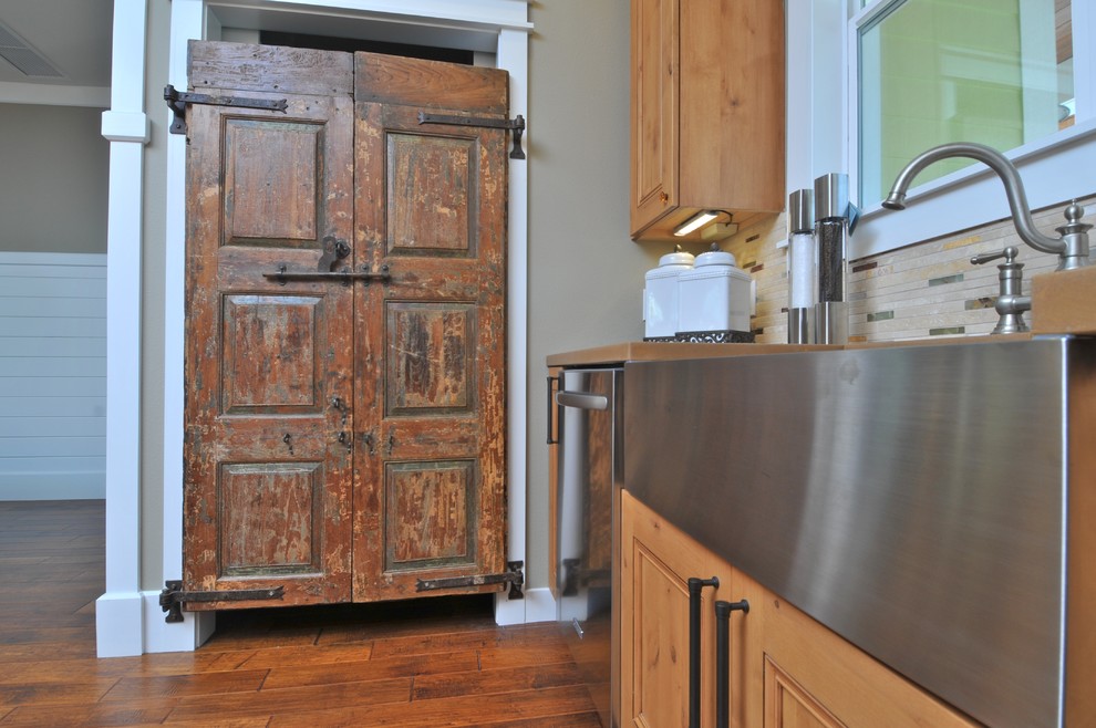 This is an example of a mid-sized arts and crafts l-shaped kitchen pantry in Tampa with a farmhouse sink, raised-panel cabinets, medium wood cabinets, concrete benchtops, multi-coloured splashback, matchstick tile splashback, stainless steel appliances, medium hardwood floors and with island.