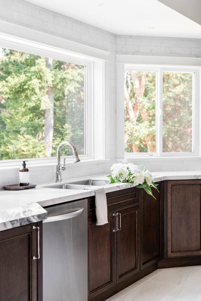 Large transitional u-shaped porcelain tile and white floor open concept kitchen photo in Vancouver with an undermount sink, recessed-panel cabinets, dark wood cabinets, quartz countertops, white backsplash, ceramic backsplash, stainless steel appliances, an island and white countertops