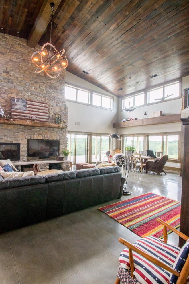 Medium sized rustic open plan living room in Cedar Rapids with beige walls, concrete flooring, a standard fireplace, a stone fireplace surround, grey floors, a vaulted ceiling and a built-in media unit.