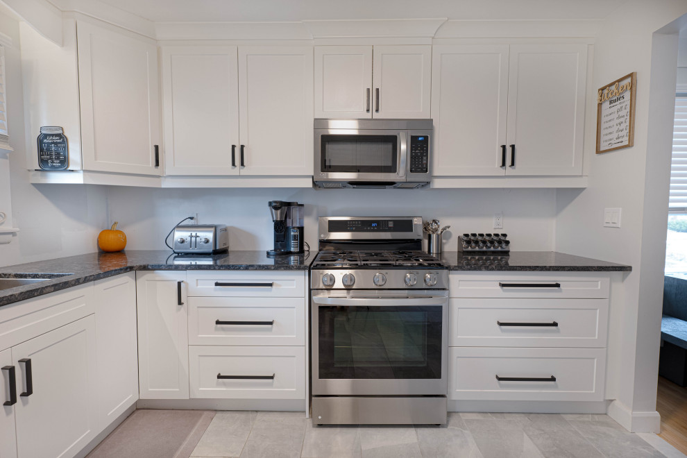 Small transitional l-shaped enclosed kitchen photo with a double-bowl sink, shaker cabinets, white cabinets, quartz countertops, stainless steel appliances, no island and black countertops