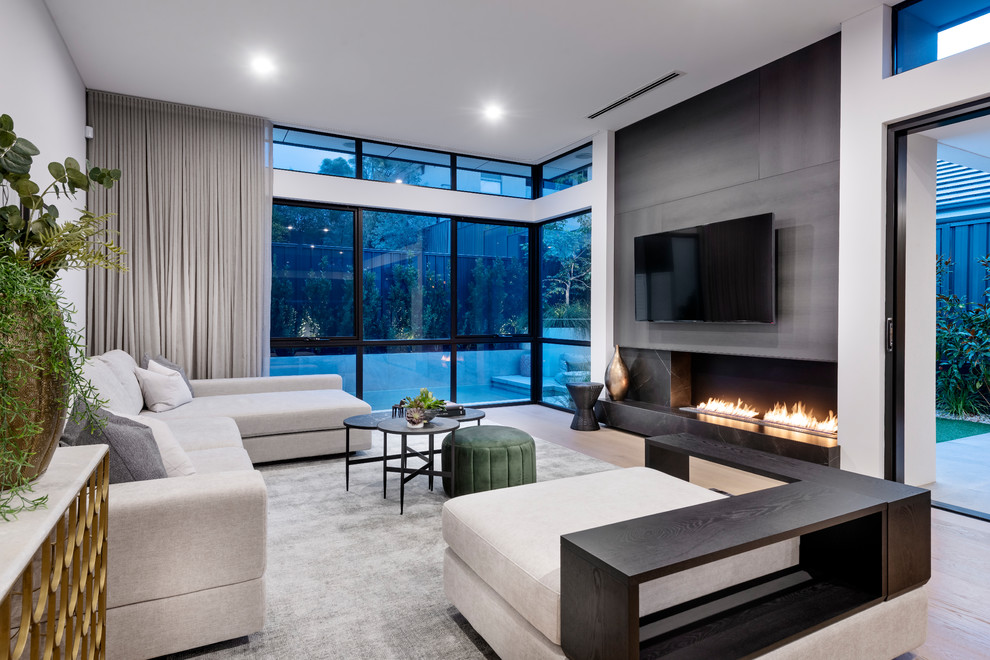 Inspiration for a contemporary living room in Perth with white walls, light hardwood floors, a ribbon fireplace, a wall-mounted tv and beige floor.